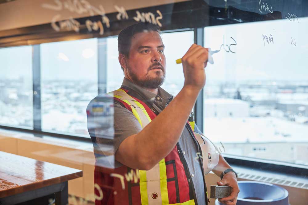 man in construction outfit writing on white board